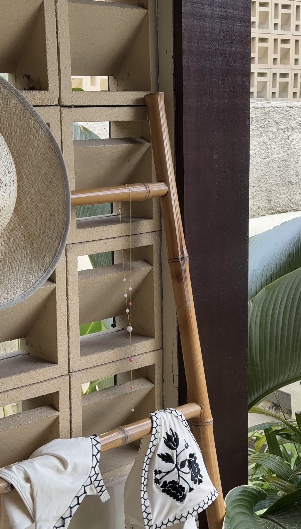 Sunhat, bikini and necklace styled on a bamboo rack
