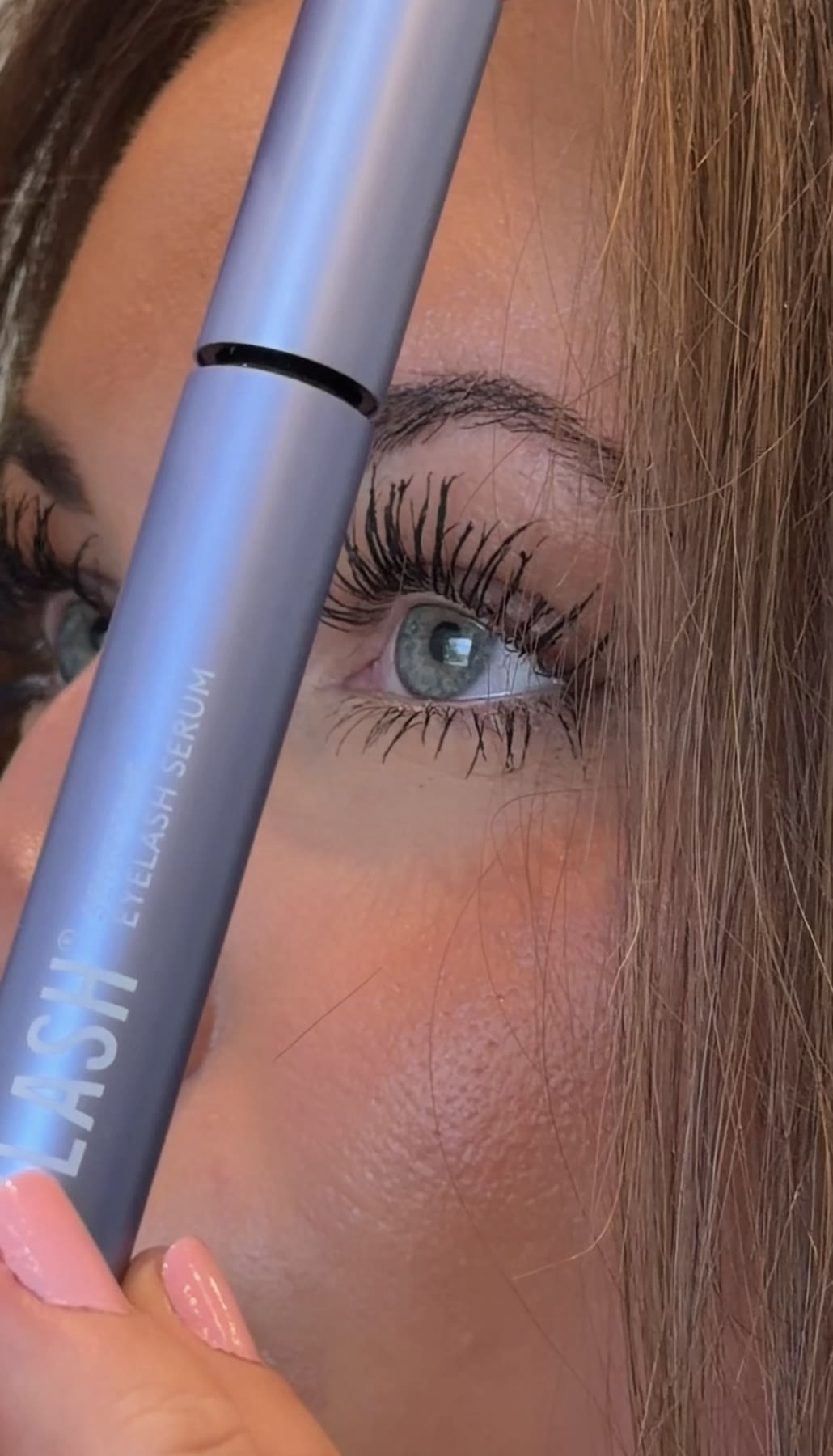 Close-up of an eye with purple eyelash serum packaging