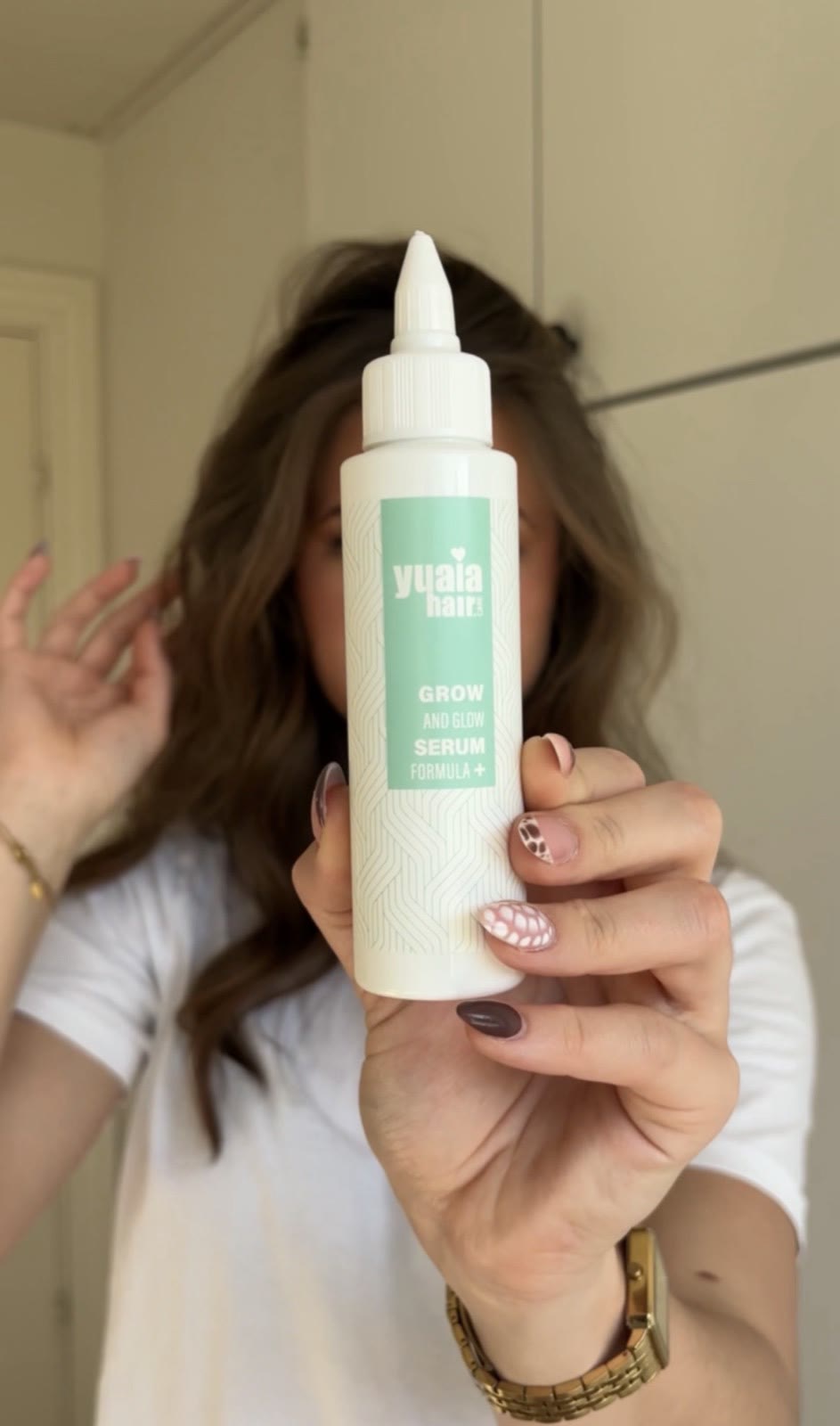 Julie holding a haircare product in front of her face